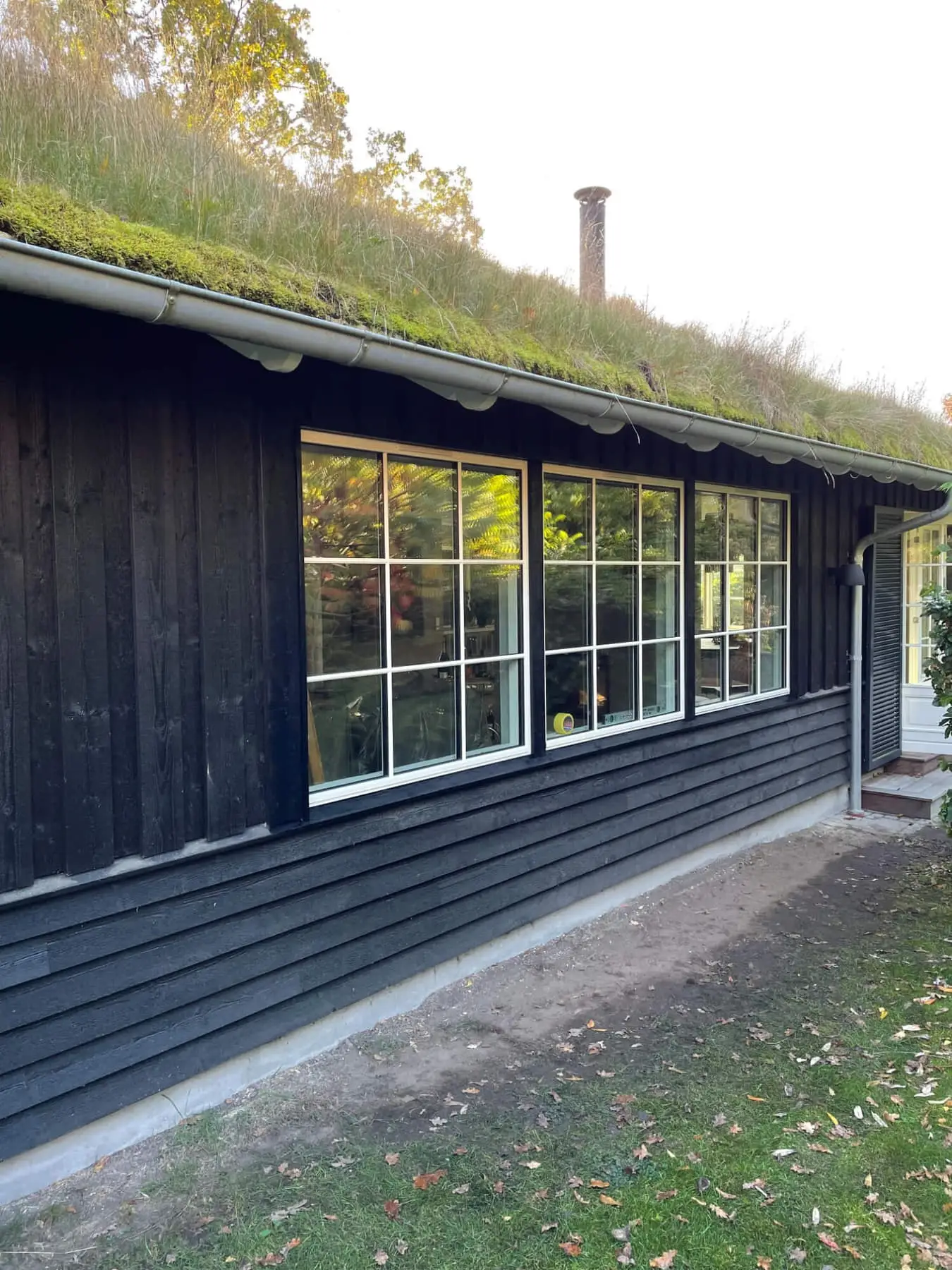 Sortmalet hus med grønt tag og en lang vinduesrække, bygget af Nesager Byg