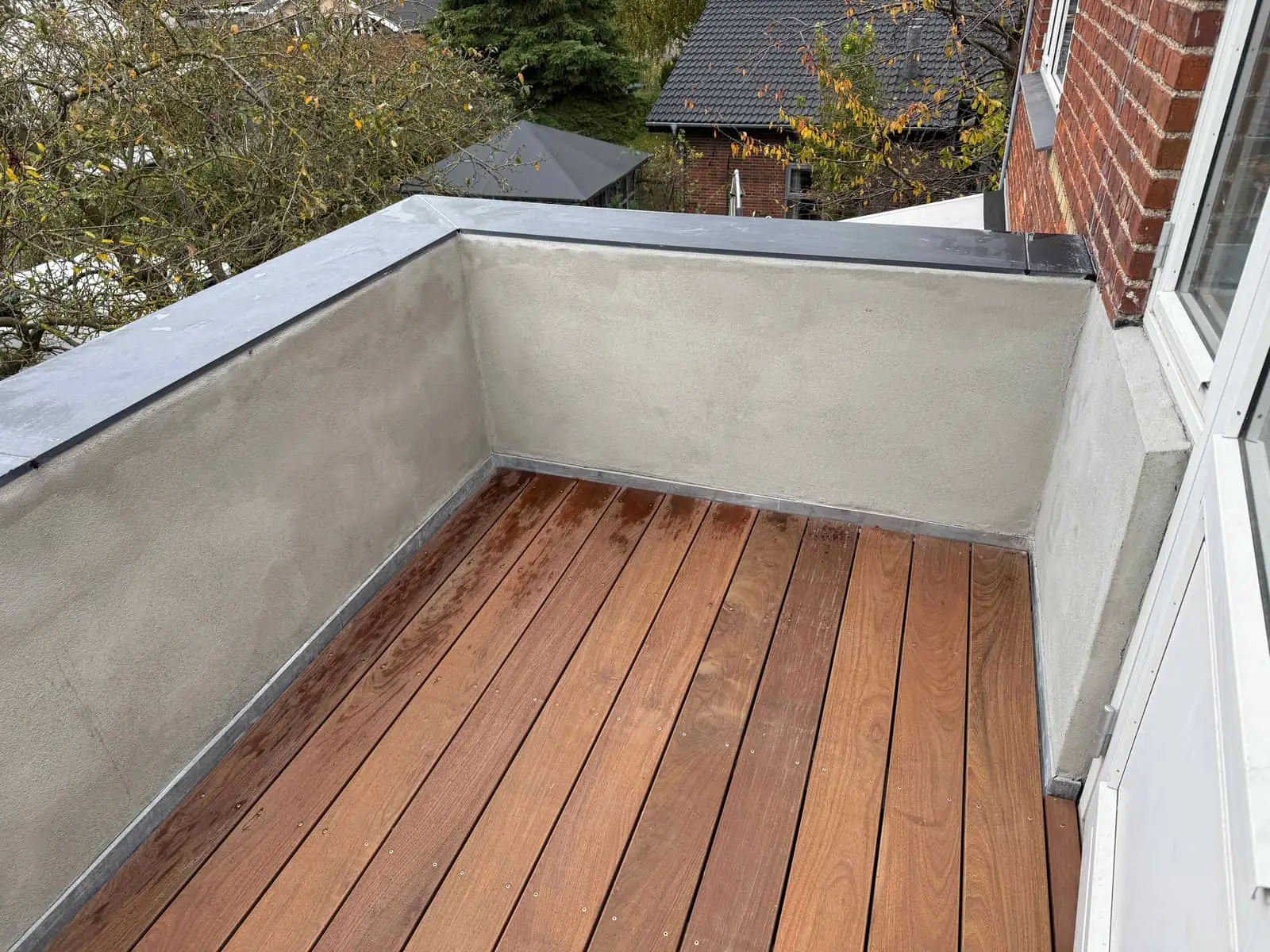 Terrasse i hårdttræ mellem pudsede mure ved hoveddøren