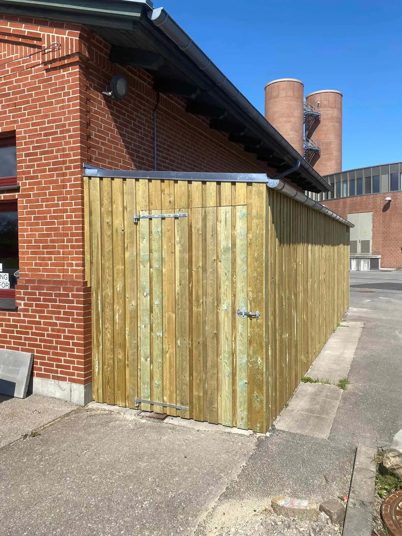 Afskærmning i lyst træ op ad en murstensfacade